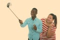 Happy young black African man and young fat Asian woman smiling while giving peace sign and taking selfie picture with Royalty Free Stock Photo