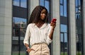 Happy young black business woman using mobile phone standing outdoors. Royalty Free Stock Photo