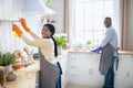 Happy young black couple cleaning their kitchen together, copy space. Housecleaning service concept