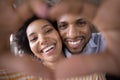 Happy young Black couple faces in finger heart shaped frame