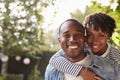 Happy young black couple piggyback in garden, look to camera Royalty Free Stock Photo