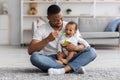 Happy Young Black Dad Spoon Feeding His Adorable Baby Son At Home Royalty Free Stock Photo