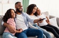 Happy young black family watching television sitting on sofa Royalty Free Stock Photo