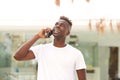 Happy young black guy standing outdoors and making a phone call Royalty Free Stock Photo