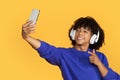 Happy young black guy wearing wireless headphones taking selfie with smartphone Royalty Free Stock Photo