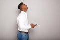 Happy young black man holding cellphone by gray wall Royalty Free Stock Photo