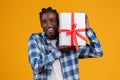 Happy young black man holding gift box with ribbon Royalty Free Stock Photo