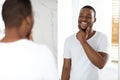Happy Young Black Man Looking In Mirror In Bathroom And Touching Face Royalty Free Stock Photo