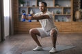 Happy Young Black Man Making Squats And Training With Dumbbells At Home Royalty Free Stock Photo