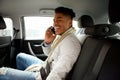 Happy young black man sitting in backseat of car and talking with mobile phone Royalty Free Stock Photo