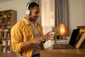 Happy young black man using laptop, wearing headphones, having video chat at home, copy space Royalty Free Stock Photo