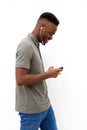 Happy young black man walking with mobile and earphones against white wall Royalty Free Stock Photo