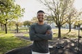 Happy young black man in sports clothing looking at camera with arms crossed in park Royalty Free Stock Photo