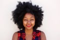 Happy young black woman with afro hairstyle by white wall