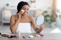 Happy young black woman applying make up and smiling Royalty Free Stock Photo