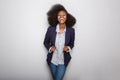 Happy young black woman with blazer against gray background