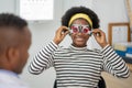 Happy Young black woman checking vision with eye test glasses during a medical examination at the ophthalmological office,