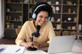 Happy young Black woman in headphones and professional microphone recording