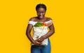 Happy Young Black Woman Holding Eco Bag With Groceries On Yellow Background
