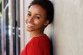 Happy young black woman leaning against wall and smiling Royalty Free Stock Photo