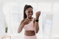 Happy young black woman pointing at activity fitness tracker with mockup, having break in her training at home Royalty Free Stock Photo