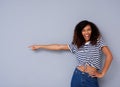 Happy young black woman smiling and pointing against copy space on gray background Royalty Free Stock Photo