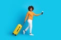 Happy young black woman traveller walking on blue, copy space Royalty Free Stock Photo