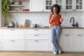 Happy Young Black Woman Using Smartphone And Drinking Morning Coffee In Kitchen Royalty Free Stock Photo