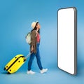 Happy young black woman walking with suitcase, checking smartphone screen Royalty Free Stock Photo