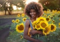 Happy young black woman walks in the sunflower field. Smiling dark-skinned girl with with a bouquet of sunflowers and Royalty Free Stock Photo