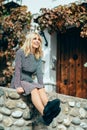 Happy young blond woman sitting on urban autumn background.