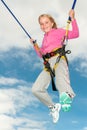 A happy young blonde girl bouncing while attached to bungee cords