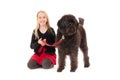 Happy young blonde girl holding black labradoodle on a red leash