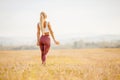 Happy young blonde girl holds water bottle in park, back frame