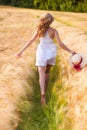 Happy young blonde girl in white dress with straw hat running th Royalty Free Stock Photo