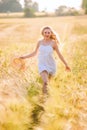 Happy young blonde girl in white dress with straw hat running th Royalty Free Stock Photo