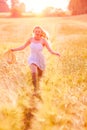 Happy young blonde girl in white dress with straw hat running th Royalty Free Stock Photo