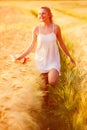 Happy young blonde girl in white dress with straw hat running th Royalty Free Stock Photo