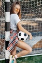 Happy young blonde hipster girl posing with soccer ball in front of goal post at the stadium. Freedom concept. Royalty Free Stock Photo
