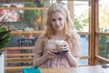 Happy young blonde woman drinking coffee in city street cafe Royalty Free Stock Photo