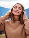 Happy young blonde woman looking at camera and smiling with teeth. Portrait of a beautiful girl in the mountains. Hair blowing Royalty Free Stock Photo