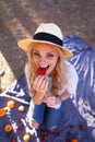 Happy blonde woman at picnic biting into strawberry