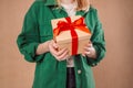 Happy young blonde woman 20s wears green denim jacket hold shake red present box with gift ribbon bow try to guess what