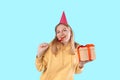 Happy young blonde woman 20s wears green denim jacket hold shake red present box with gift ribbon bow try to guess what