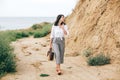 Happy young boho woman in white shirt walking on tropical island at sandy cliff and grass. Stylish hipster girl relaxing on beach Royalty Free Stock Photo