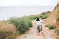 Happy young boho woman in white shirt walking on tropical island at sandy cliff and grass. Stylish hipster girl relaxing on beach Royalty Free Stock Photo