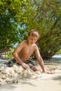 happy young boy is digging in the sand of the beach and constructing sand buildings Royalty Free Stock Photo
