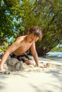 happy young boy is digging in the sand of the beach and constructing sand buildings Royalty Free Stock Photo