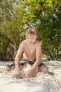 Happy young boy is digging in the sand of the beach Royalty Free Stock Photo