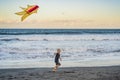 Happy young boy flying kite on the beach at sunset Royalty Free Stock Photo